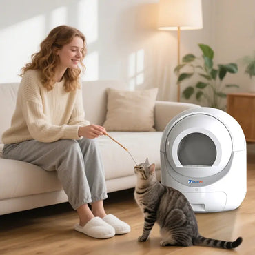 Woman playing with her cat next to an automatic self-cleaning litter box in the living room
